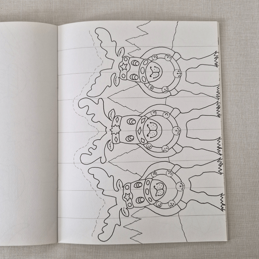 Open book with a colouring christmas card of reindeer on a textured fabric background