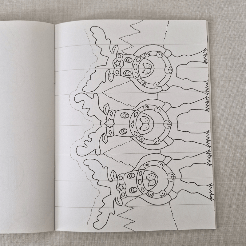 Open book with a colouring christmas card of reindeer on a textured fabric background