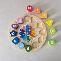 Wooden educational clock with colourful numbers and shapes on a gray background