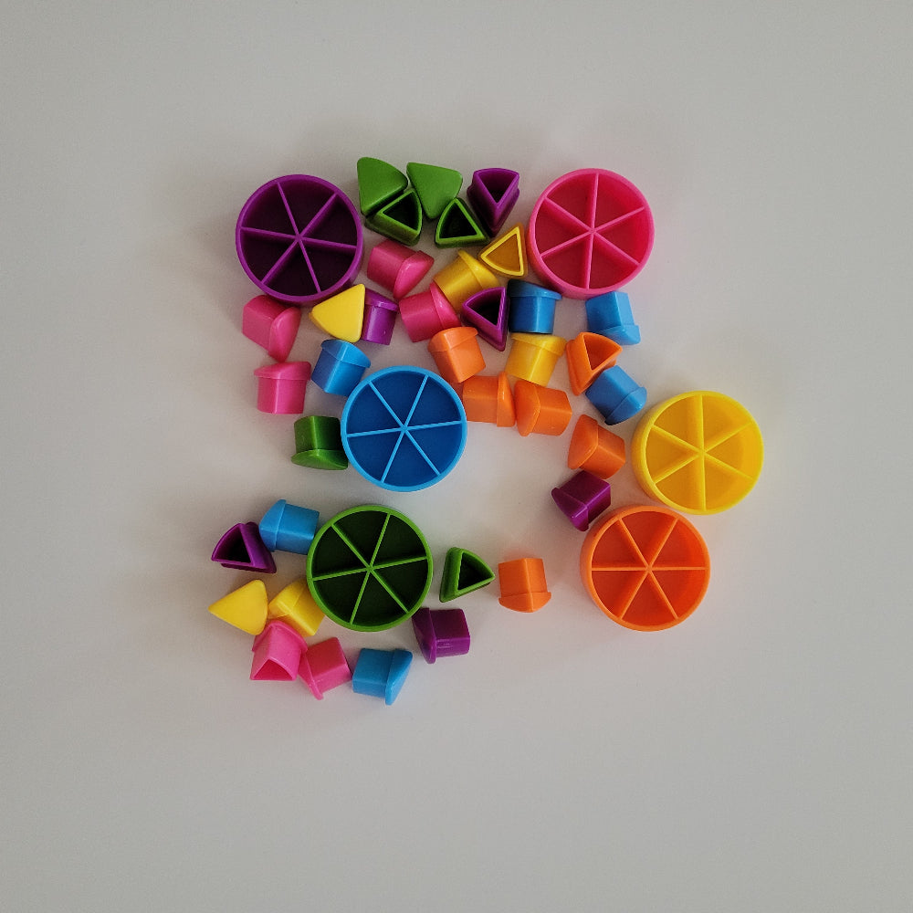 A collection of colourful plastic geometric toy pieces, including circular wheel-shaped cutters and small blocks in pink, blue, green, yellow, orange, and purple, arranged on a light gray background.