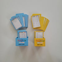 Two sets of Trivial Pursuit card games displayed on a light gray wall, featuring adult cards in a blue box and kid's cards in a yellow box, with cards fanned out above each container.