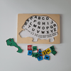 Wooden puzzle with turtle shape and alphabet letters, accompanied by a colourful letter tiles on a light grey background.