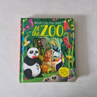 Children's book titled 'What Can You See At The Zoo' on a gray surface