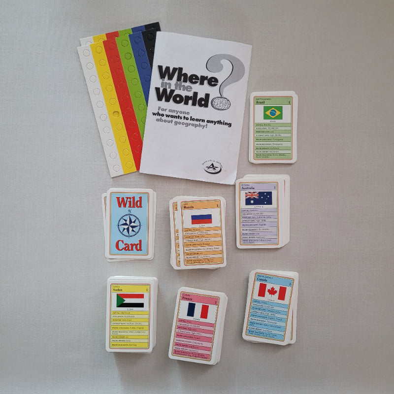 A set of educational cards and a booklet titled "Where Is the World?" arranged on a light gray surface. The set includes a white booklet, several colorful card sleeves or tabs in red, yellow, green, blue, and white, and multiple white cards with different flag designs and text sections.