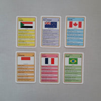 Six educational country cards arranged on a light gray textured surface. The cards feature different countries with their national flags and detailed facts printed in multicolored panels.