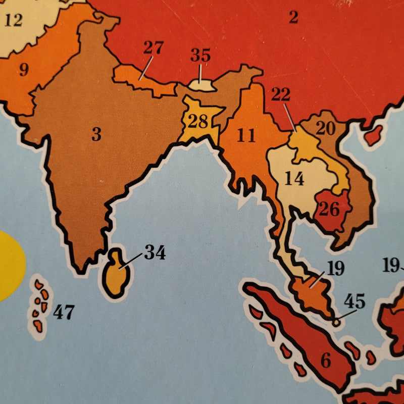 A close-up of a colorful section of map on educational board showing parts of Asia with numbered regions in red, orange, yellow, and beige on a light blue sea area.