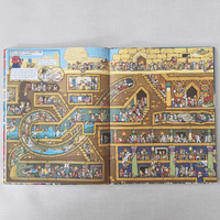 Illustrated book open to a detailed picture of a egypt tombs with various rooms and characters on a grey background.