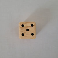 Wooden die with black dots on a gray background