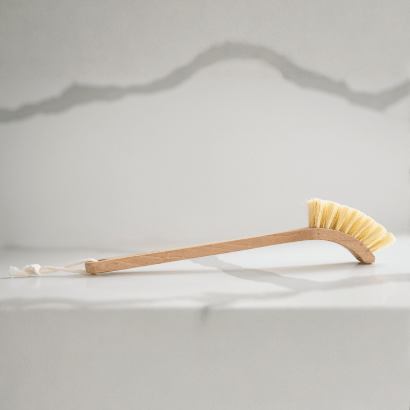 Cleaning brush with yellow bristles on a white surface
