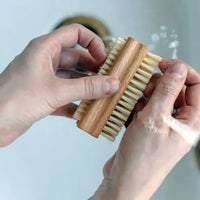 Person holding a wooden brush with bristles against a light background