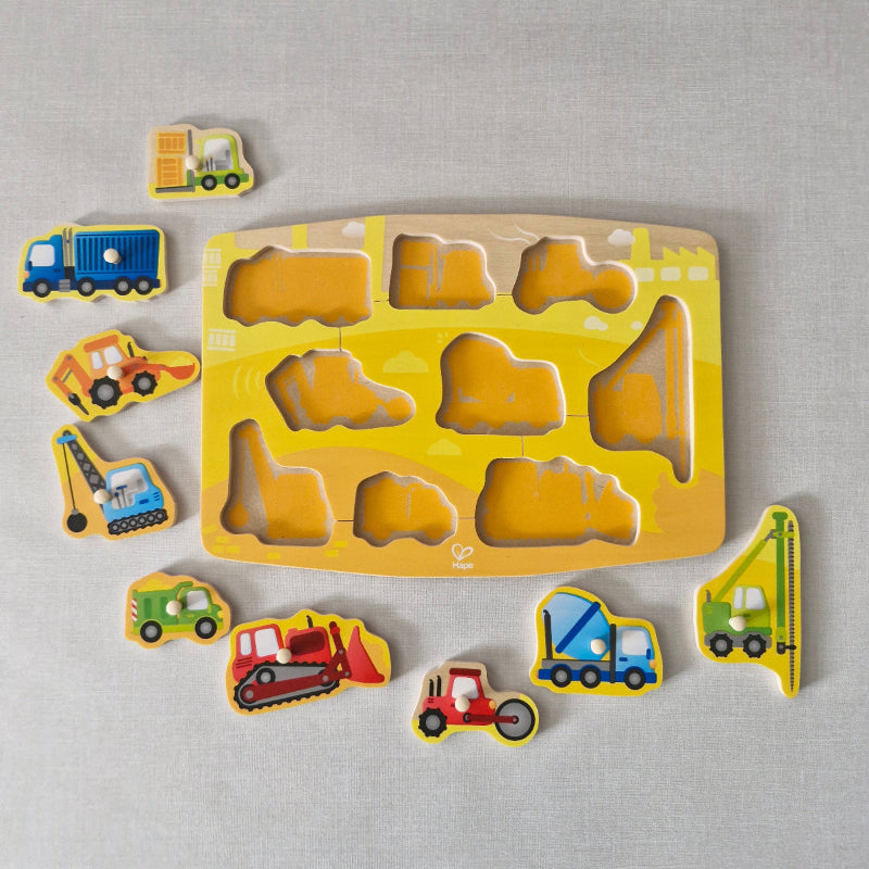 Wooden puzzle with construction vehicle shapes on a gray background
