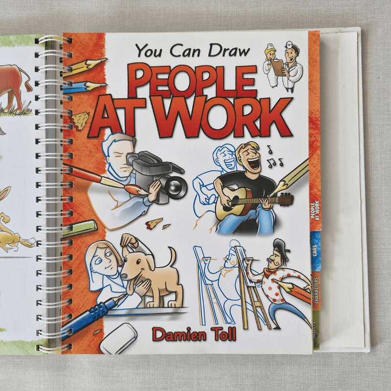 Book titled 'You Can Draw People at Work' by Damien Toll on a grey surface
