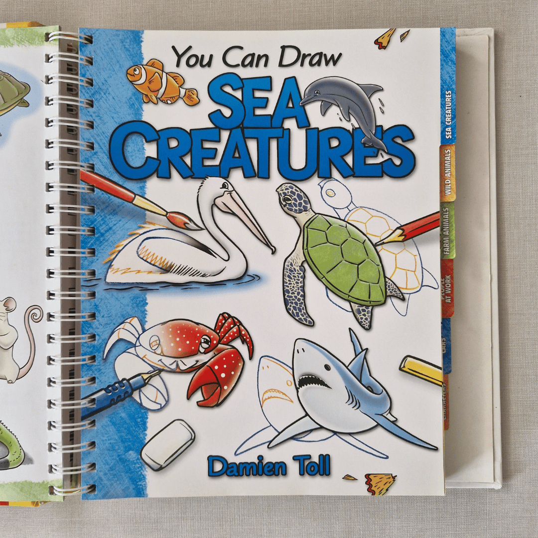 Book titled 'You Can Draw Sea Creatures' by Damien Toll on a textured surface