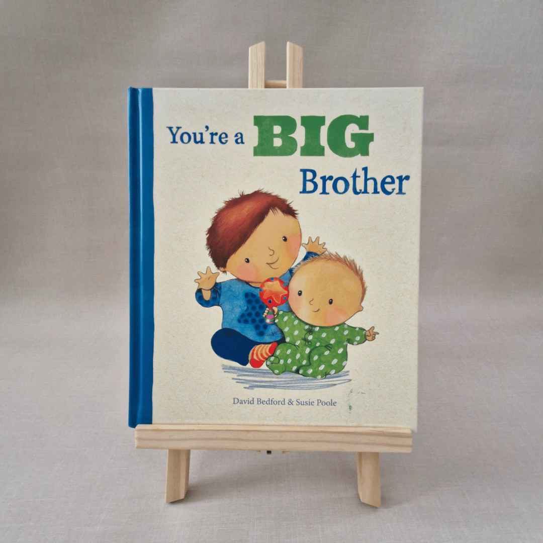 Book titled 'You're a Big Brother' on a stand with a plain background
