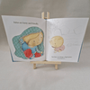 Illustrated book open to a page with two children on a small wooden stand.