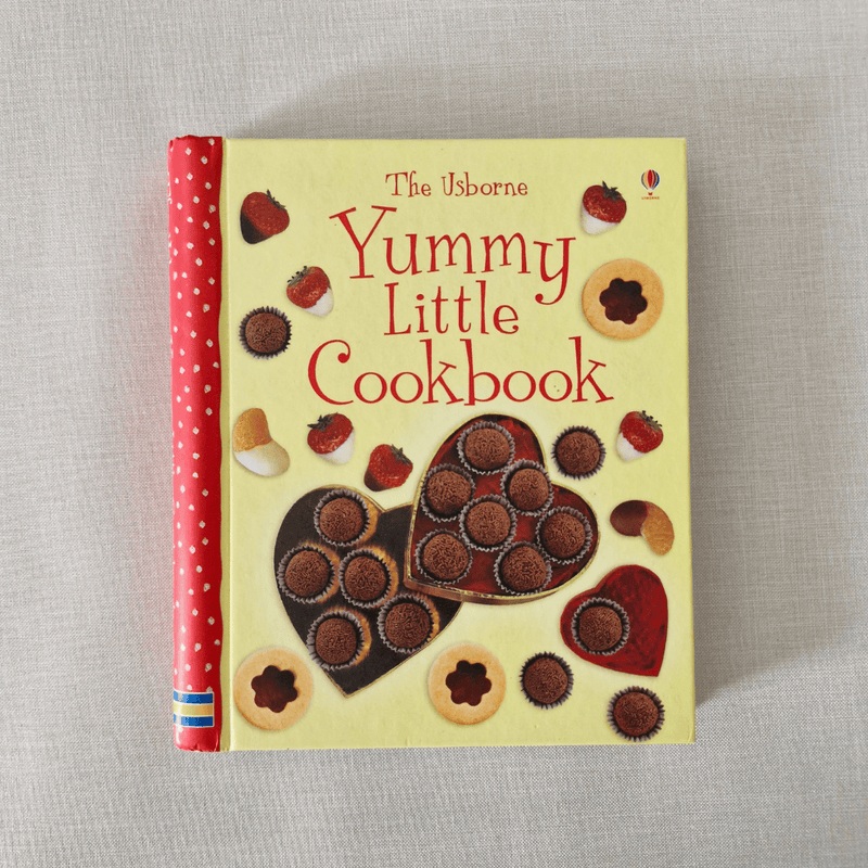 Children's cookbook titled 'Yummy Little Cookbook' with illustrations of cookies on a beige background