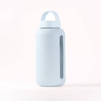 Light blue (glacier) silicone covered glass water bottle with a clear window to see water level on a white background
