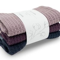 Stack of folded knitted organic cotton face cloths with a ecovask brand label on a white background