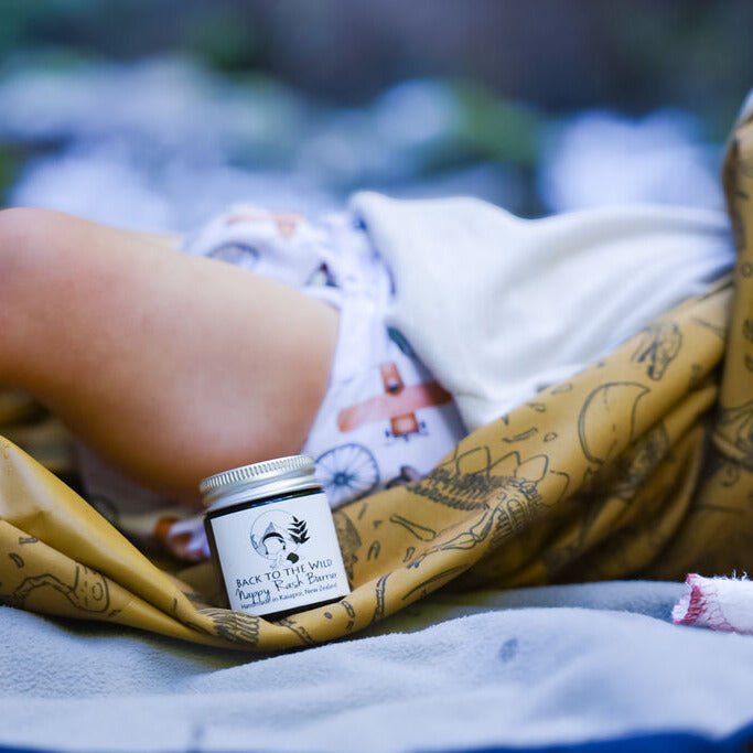 Small jar of cream with a label near a child getting changed on a change mat.