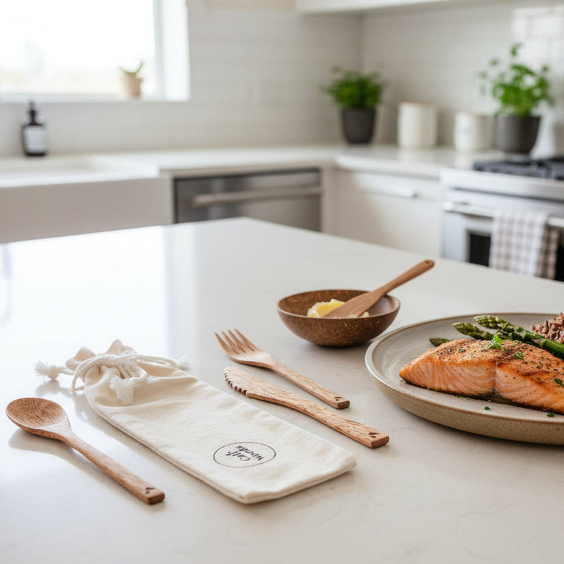 Plated dish of salmon with asparagus on a kitchen counter with wooden utensils and a cloth napkin.