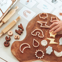 Sky themed dough cutters on wooden board with a childs hand and flash cards