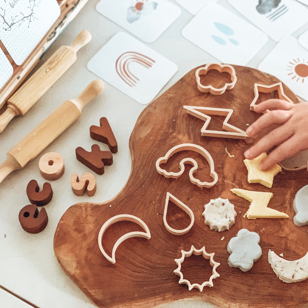 Sky themed dough cutters on wooden board with a childs hand and flash cards
