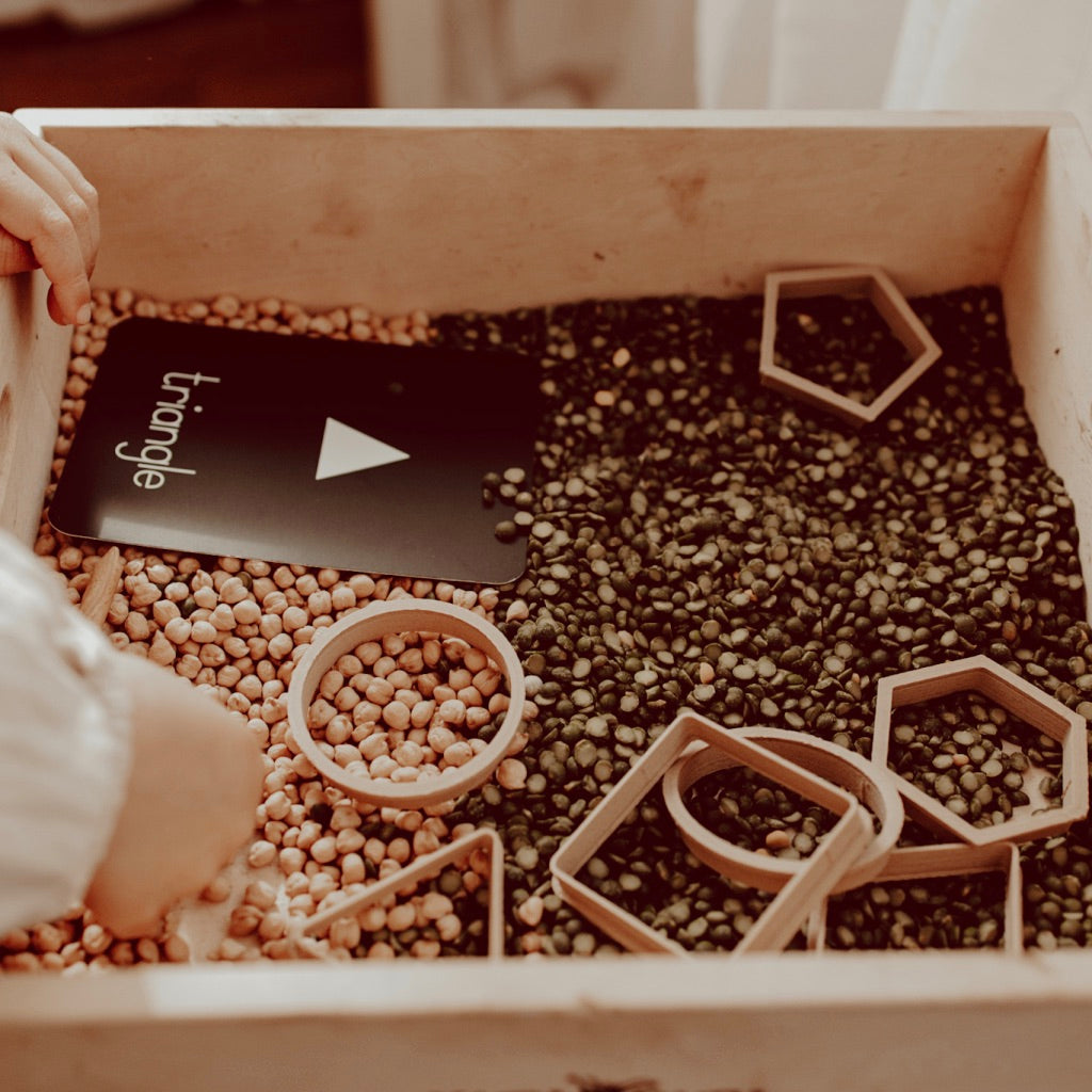 Shape dough cutters on a box of lentils with a childs hand and 'triangle' shape card