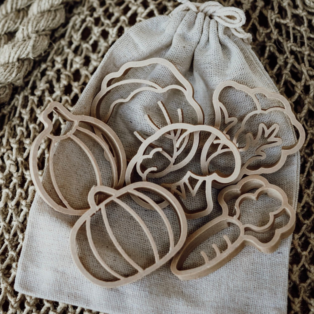 Vegetable shaped dough cutters resting on a cotton bag